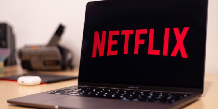 Жінка перемикається від роботи до перегляду фільму на одному ноутбуці, ілюструючи розмиті цифрові межі.