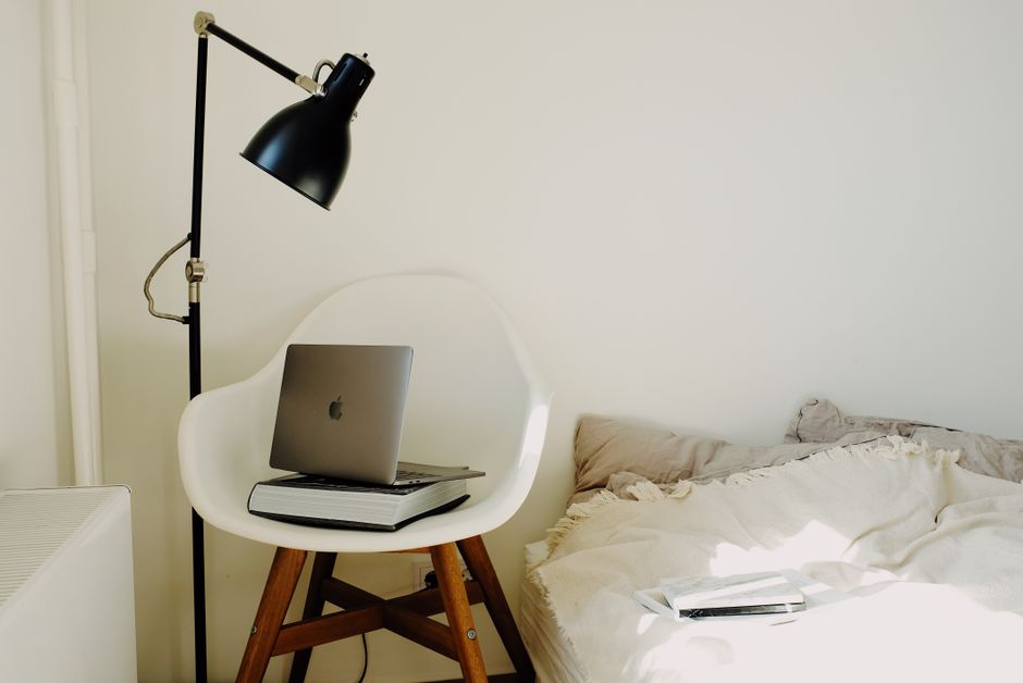 Donna che lavora al laptop in un piccolo appartamento italiano, con piante e libri sullo sfondo.