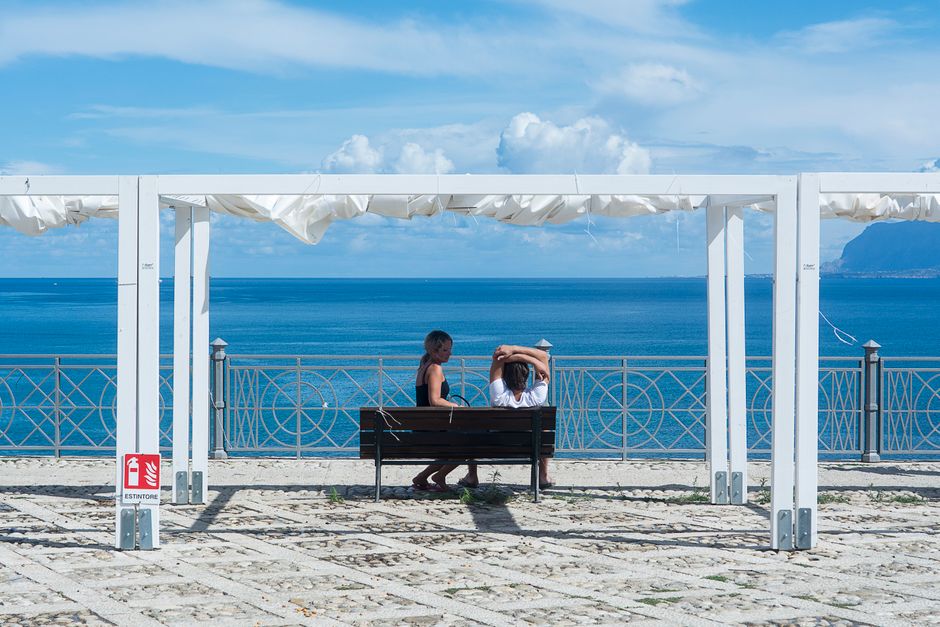 Una coppia sorridente che gusta un aperitivo con Spritz e stuzzichini su una terrazza italiana al tramonto