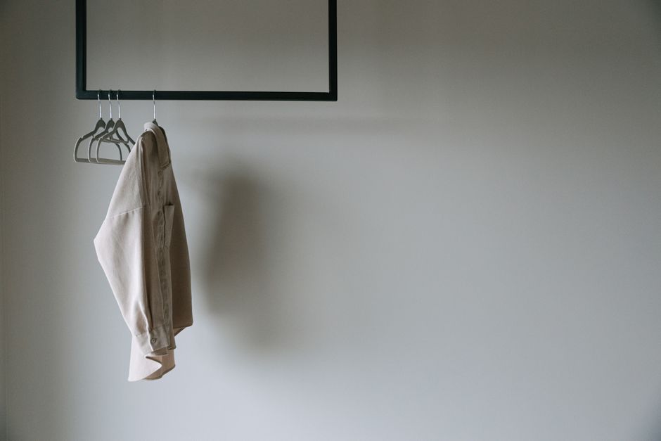 Detailní pohled na kapslový šatník s několika minimalistickými kousky oblečení na ramínku.