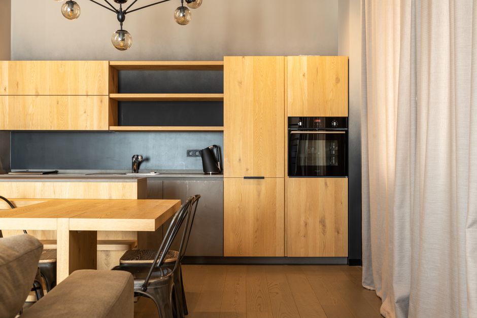 Interno di una cucina moderna e compatta in un appartamento di città, con scaffali aperti e contenitori organizzati, che riflette l'ordine di un reset stagionale.