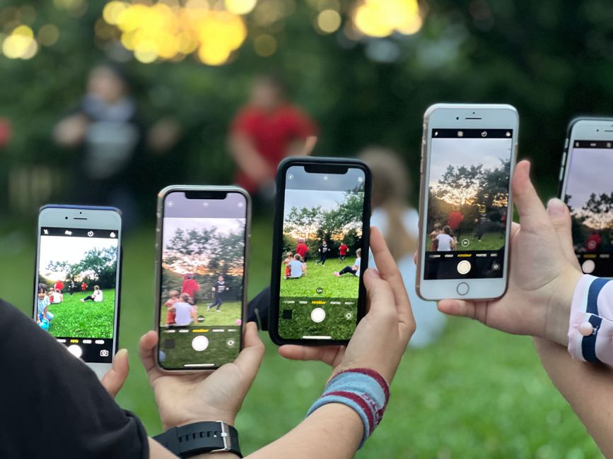 Ruce držící smartphony s různými recenzemi produktů a hvězdičkovými hodnoceními, ilustrující rozmanitost názorů online.