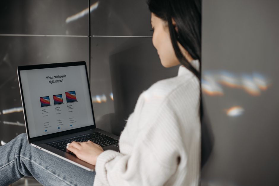 Detailní záběr rukou procházejících online nabídky a srovnání cen na notebooku. Znázorňuje chytré nakupování a rozhodování před finálním nákupem.