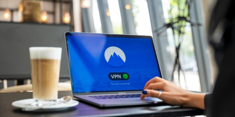Una persona che configura le impostazioni di sicurezza Wi-Fi su un laptop a casa, con un'interfaccia di router sullo schermo.