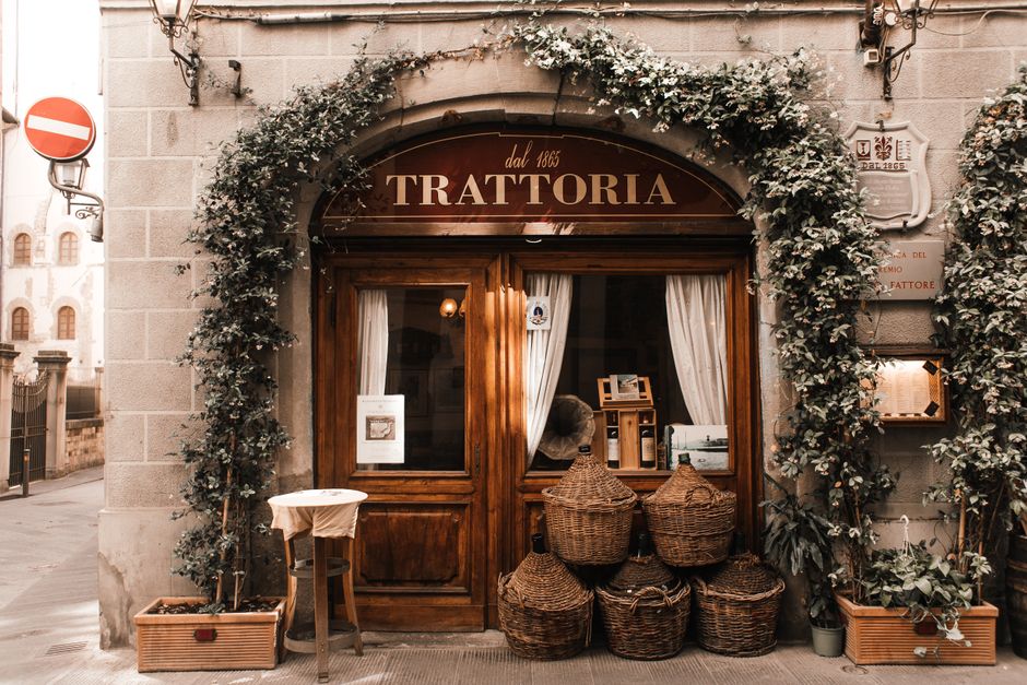 Interno accogliente di una trattoria tradizionale italiana con tavoli in legno e piatti di pasta fresca