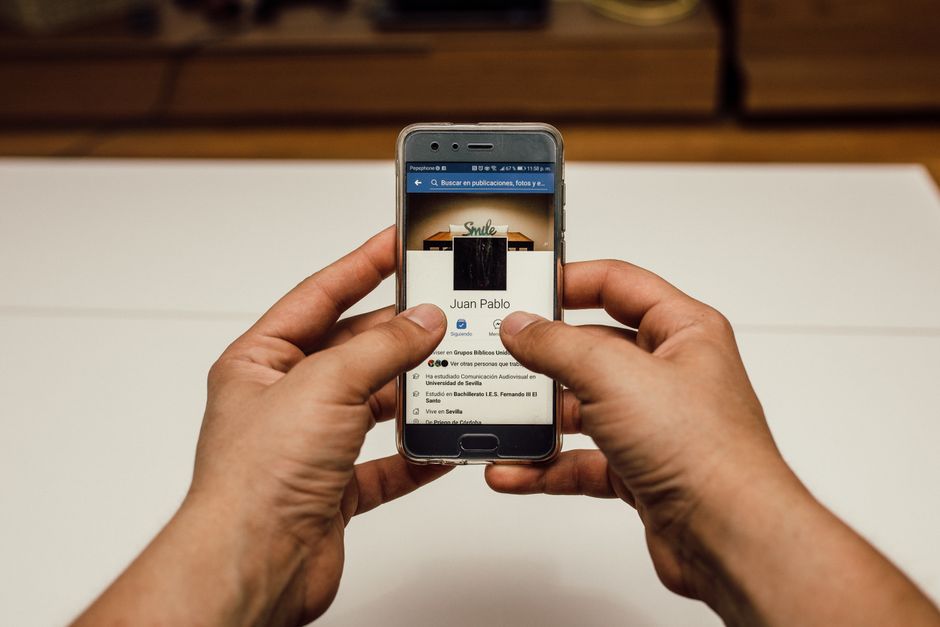 Una persona in viaggio che controlla il proprio smartphone, con un'icona Wi-Fi sicura sullo schermo, suggerendo tranquillità sulla rete domestica.