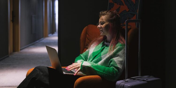 Žena kontrolující seznam předplatných na notebooku, s úsměvem, když některé zrušila