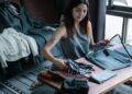 Donna che sistema gli abiti sul letto per la pianificazione outfit settimanali