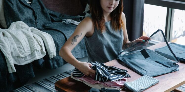 Donna che sistema gli abiti sul letto per la pianificazione outfit settimanali